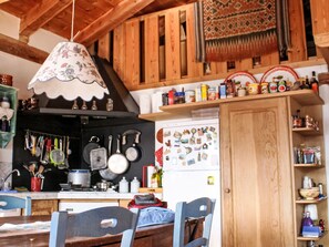 A kitchen with wooden cabinets, a hanging light fixture, and various kitchen utensils. - "Das Haus des Lichts by Interhome (Nus)