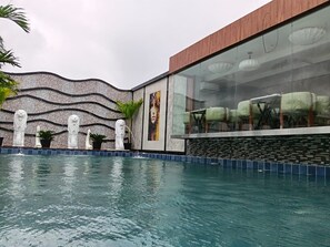 Una piscina con un muro decorativo e un'area salotto con vista sulla piscina.