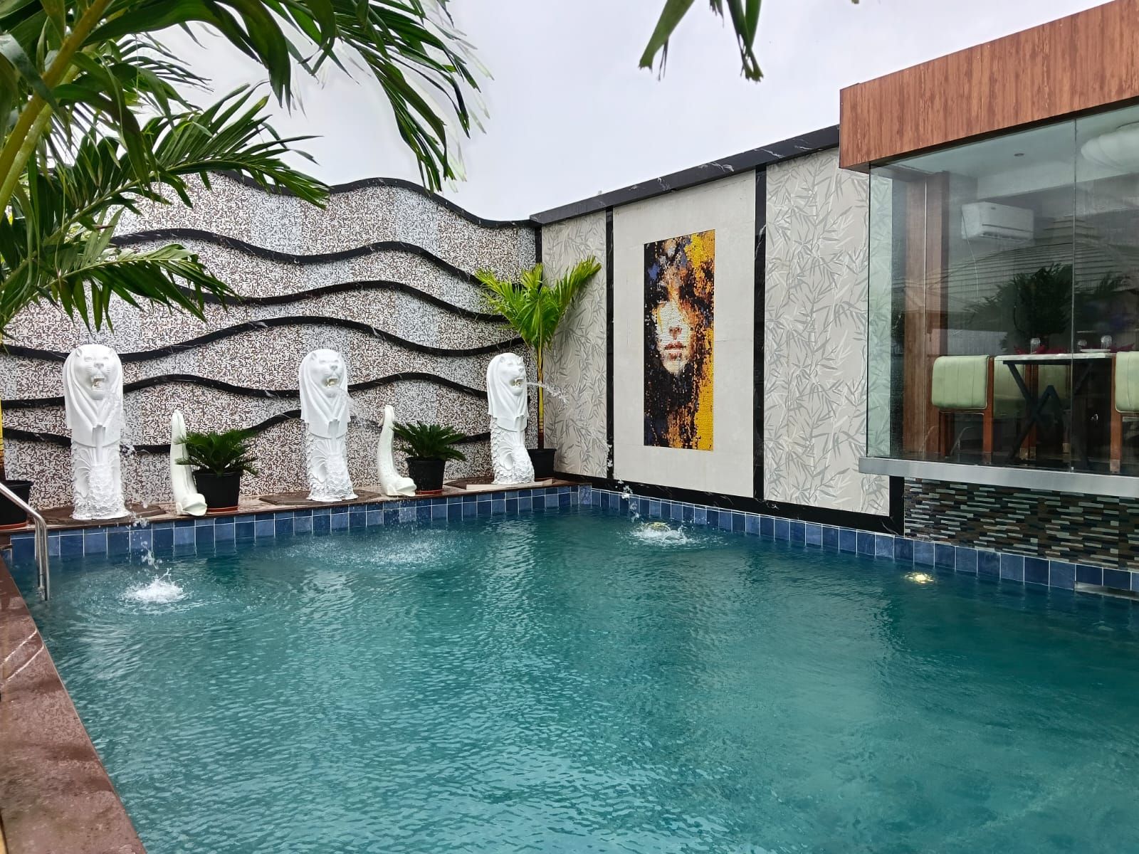 A swimming pool with decorative statues and a modern building with a glass facade.