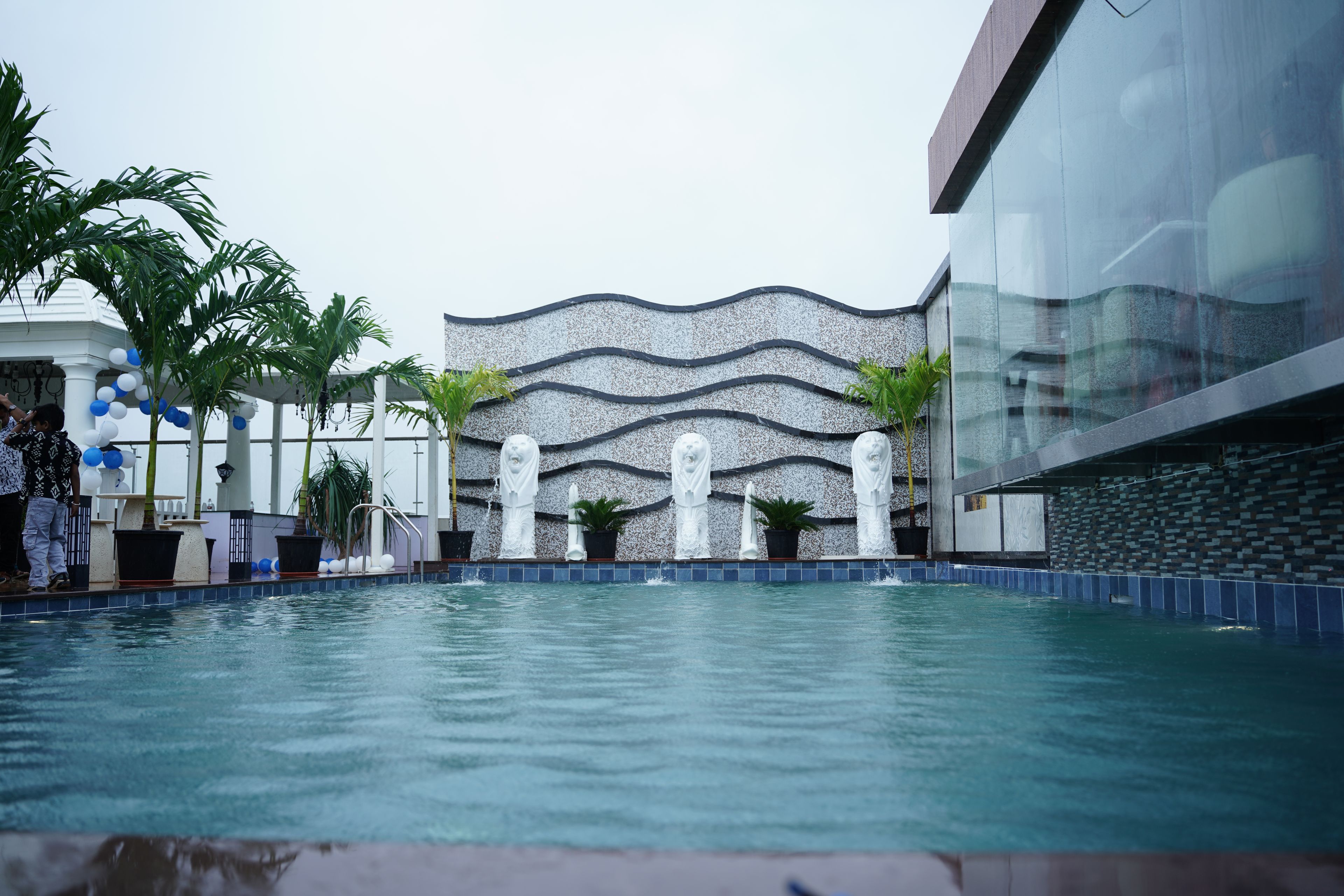 A swimming pool with a decorative wall and statues in the background.
