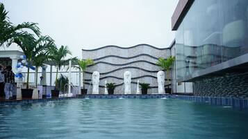 A swimming pool with a decorative wall and statues in the background.