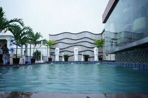 Ein Swimmingpool mit einer Zierwand und Statuen im Hintergrund.