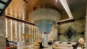 A spacious lobby with a large chandelier, marble walls, and a seating area with a sofa and armchairs. - HOTEL IMPERIAL BLU (Nandapur)