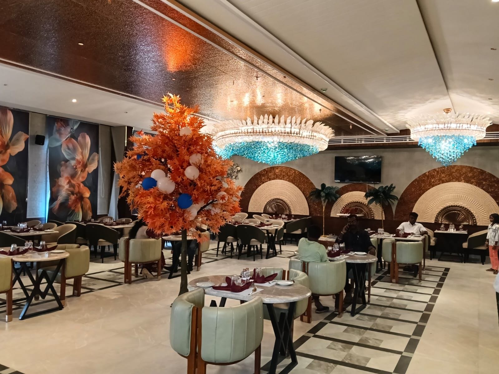 Un restaurant spacieux doté de plusieurs espaces de restauration, de compositions florales décoratives et d’élégants lustres.