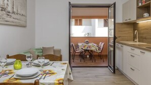 A compact dining area with a table set for four, a kitchen with white cabinets, and a painting on the wall. - Wohnung 'Silva5' mit Wasserblick by Interhome (Rovinj)
