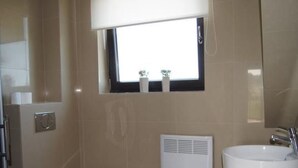 Ein Badezimmer mit Toilette, Waschbecken, Fenster und Spiegel.