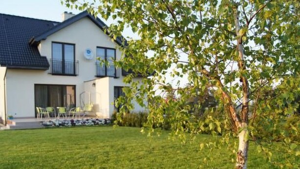 Ein modernes, zweistöckiges Haus mit gepflegtem Rasen und einem Baum im Vordergrund.