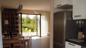 Eine moderne Küche mit einem eingebauten Kühlschrank und einer Essecke mit Tisch und Stühlen.
