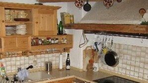 Een keuken met houten kastjes, een zwarte vaatwasser en een betegelde achterwand.