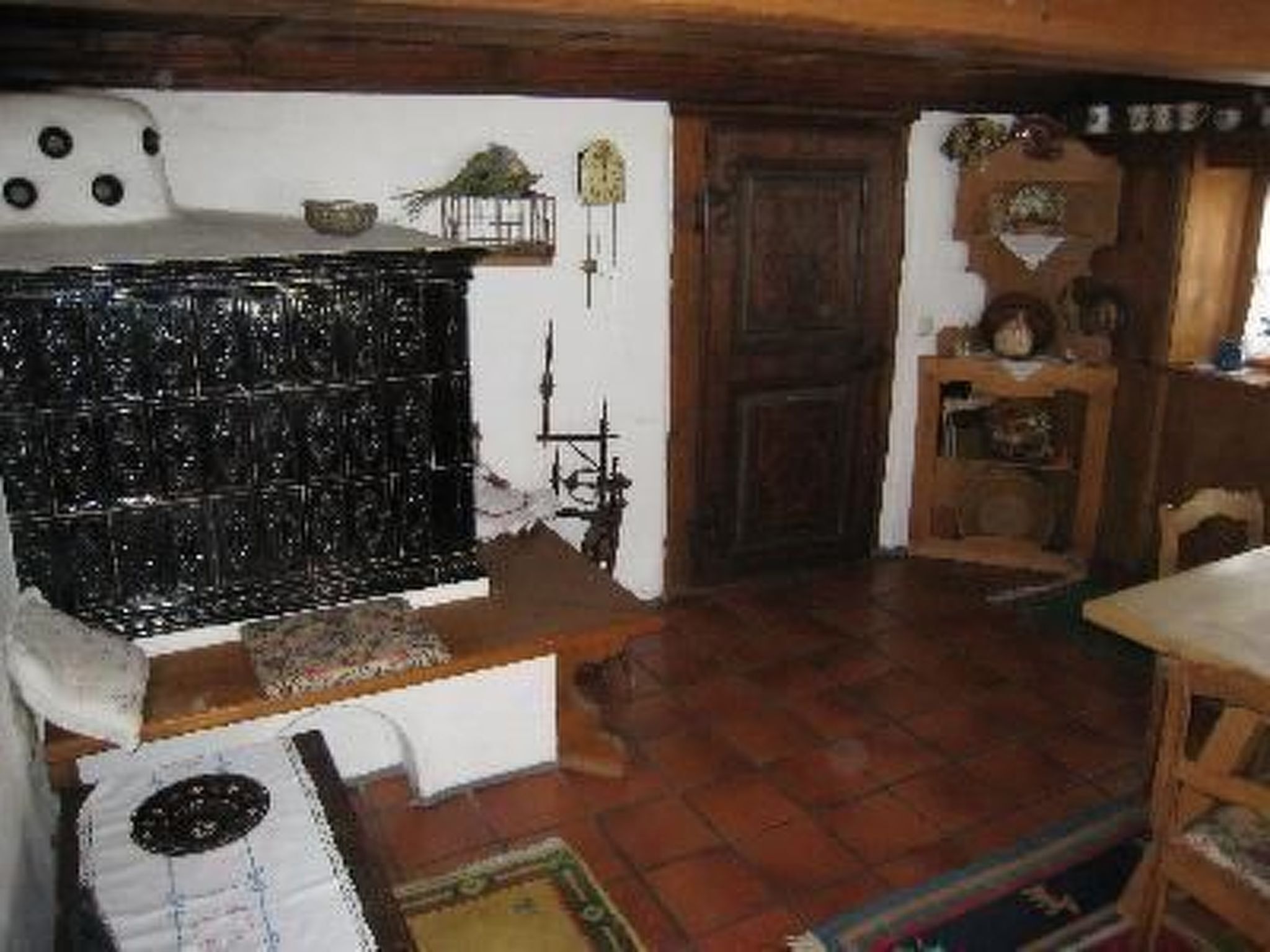 A rustic kitchen with a wooden table, a stove, and a shelf with various items.