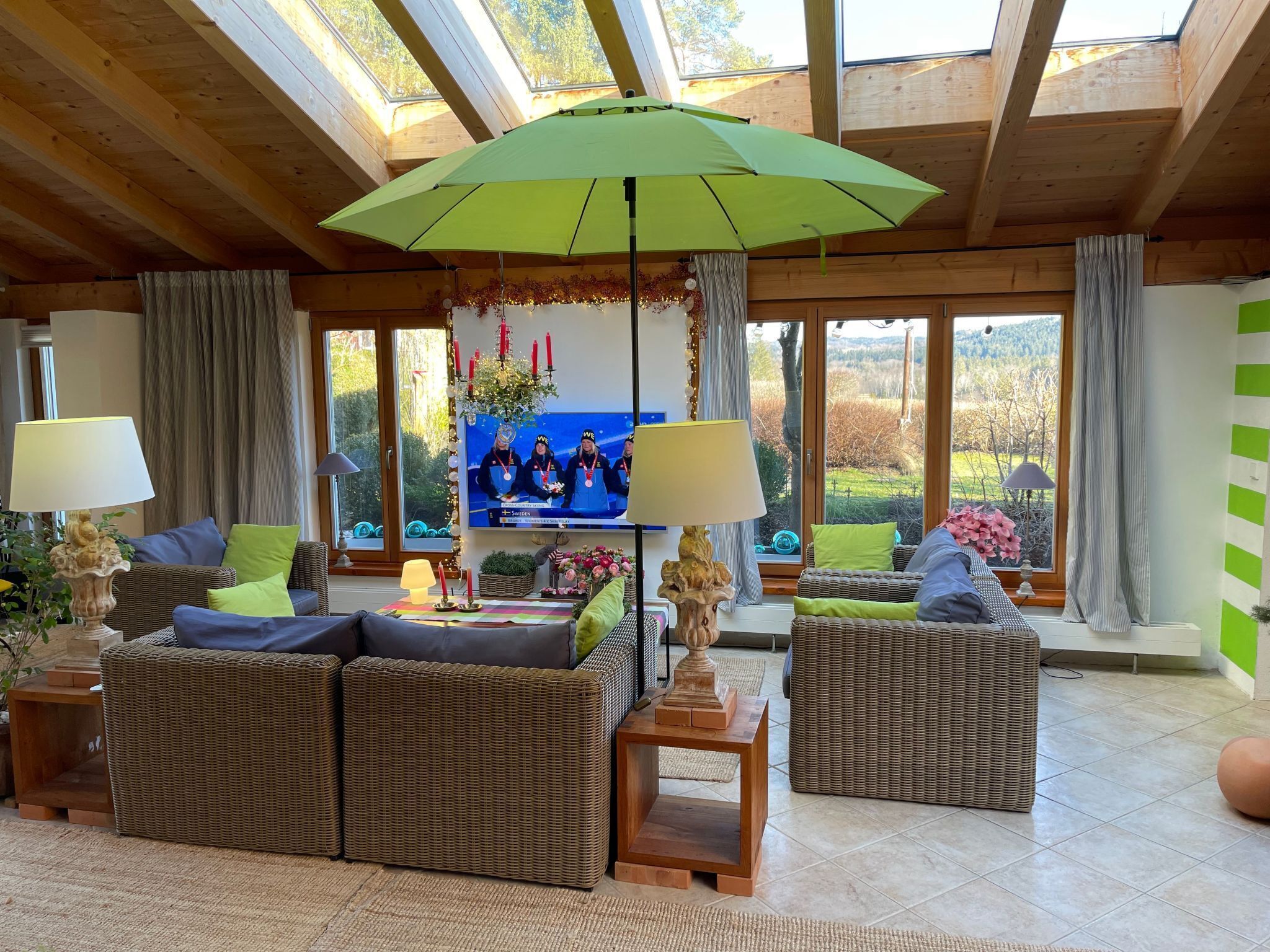 A cozy living room with wicker furniture, a large TV, and a green umbrella.