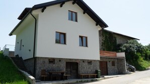 Ein zweistöckiges Gebäude mit einer steinernen Fassade, einer Holzbank vor der Tür und einer Treppe, die zum Eingang führt.