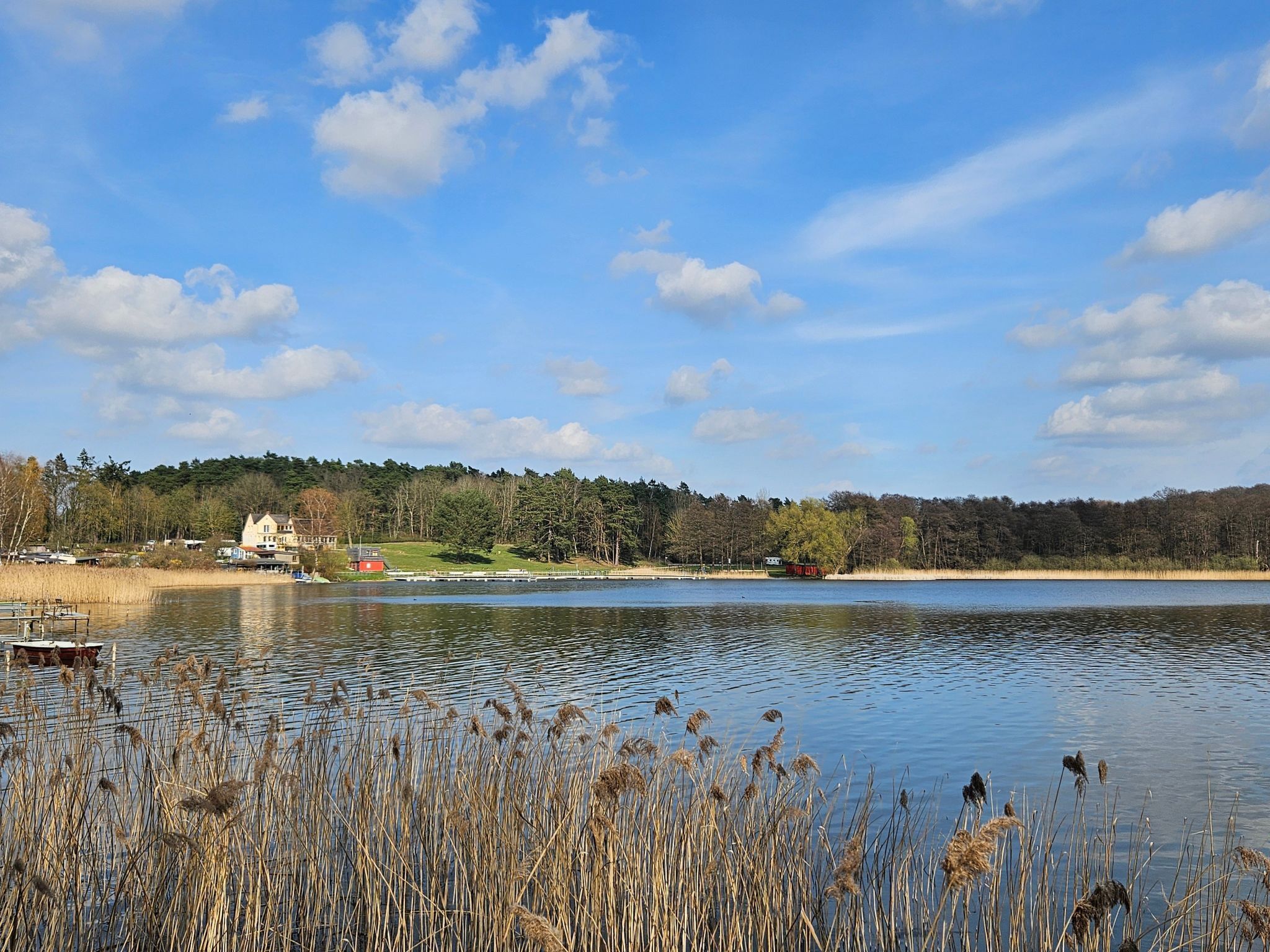 A lakeside view with a house, dock, and calm water.