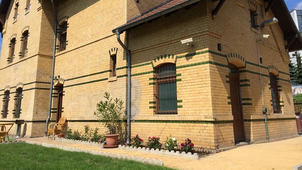 Un edificio grande de dos pisos con fachada de ladrillo y detalles decorativos verdes.