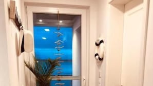 A hallway with wooden flooring, a potted plant, and a door leading to a room with a blue wall and a window. - Schwimmendes Haus Elandi by Interhome (Bitterfeld)