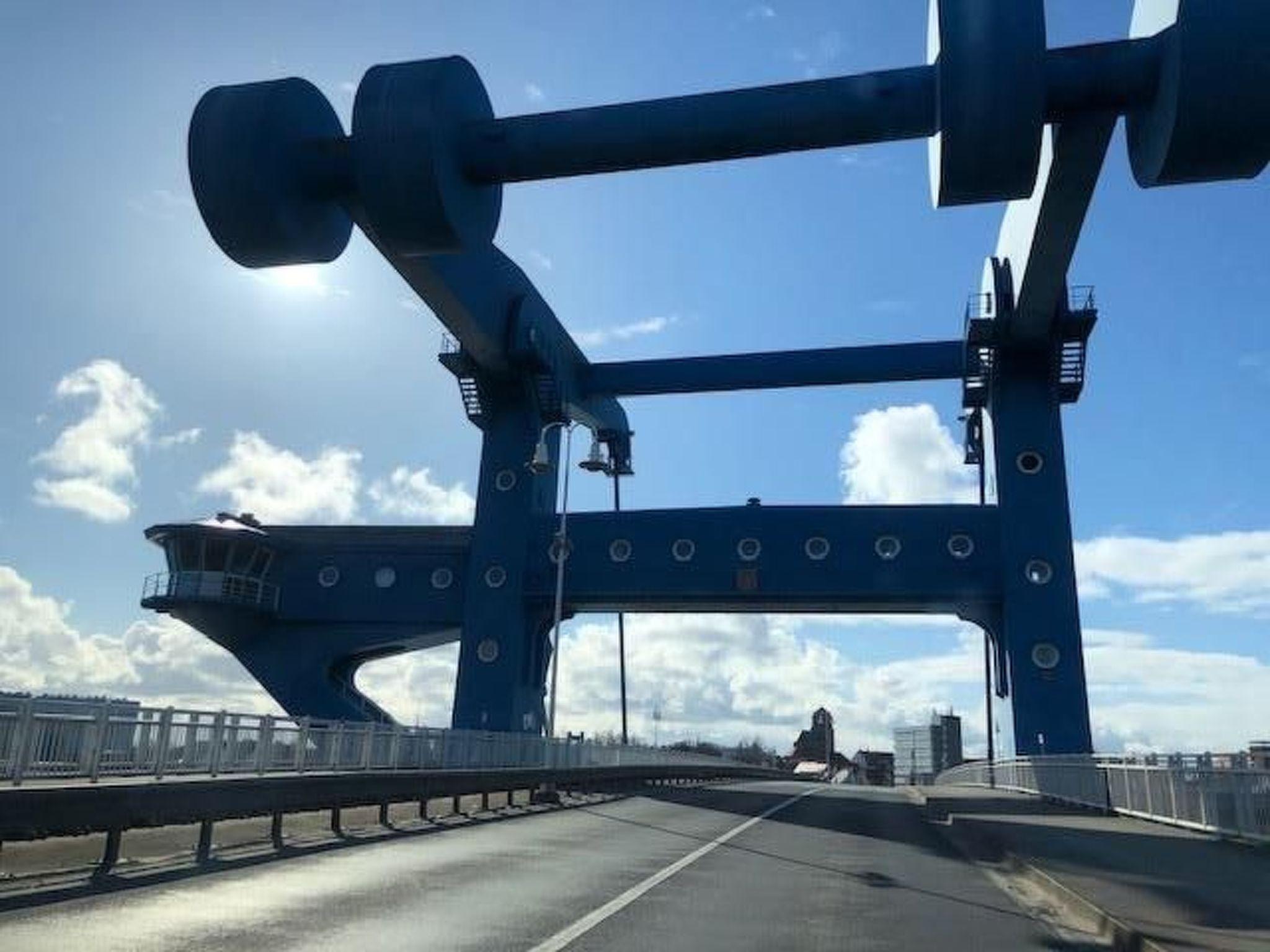 A blue bridge with a control tower and guardrails.