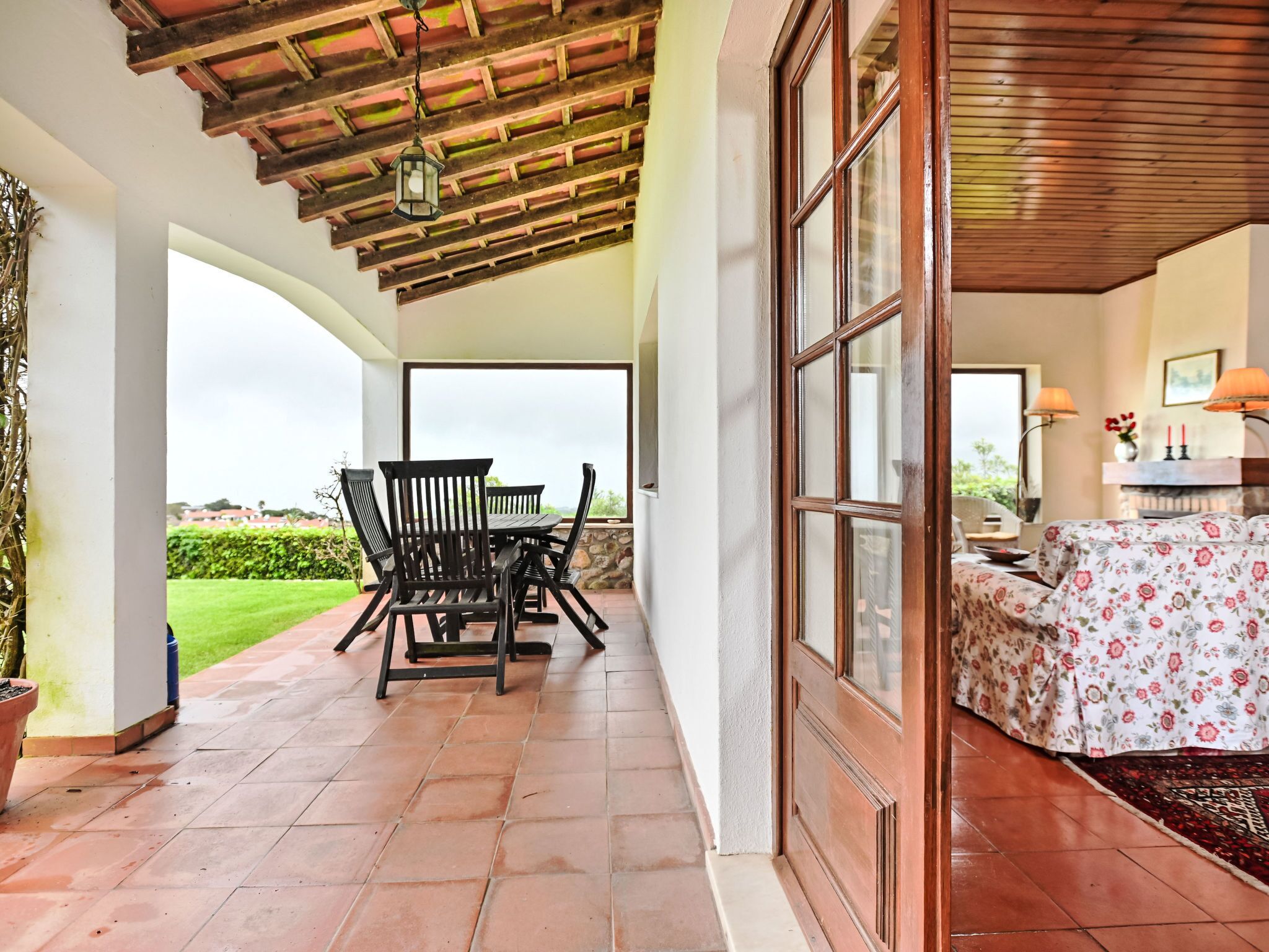 A covered patio with a table and chairs, a fireplace, and a view of the outdoors.