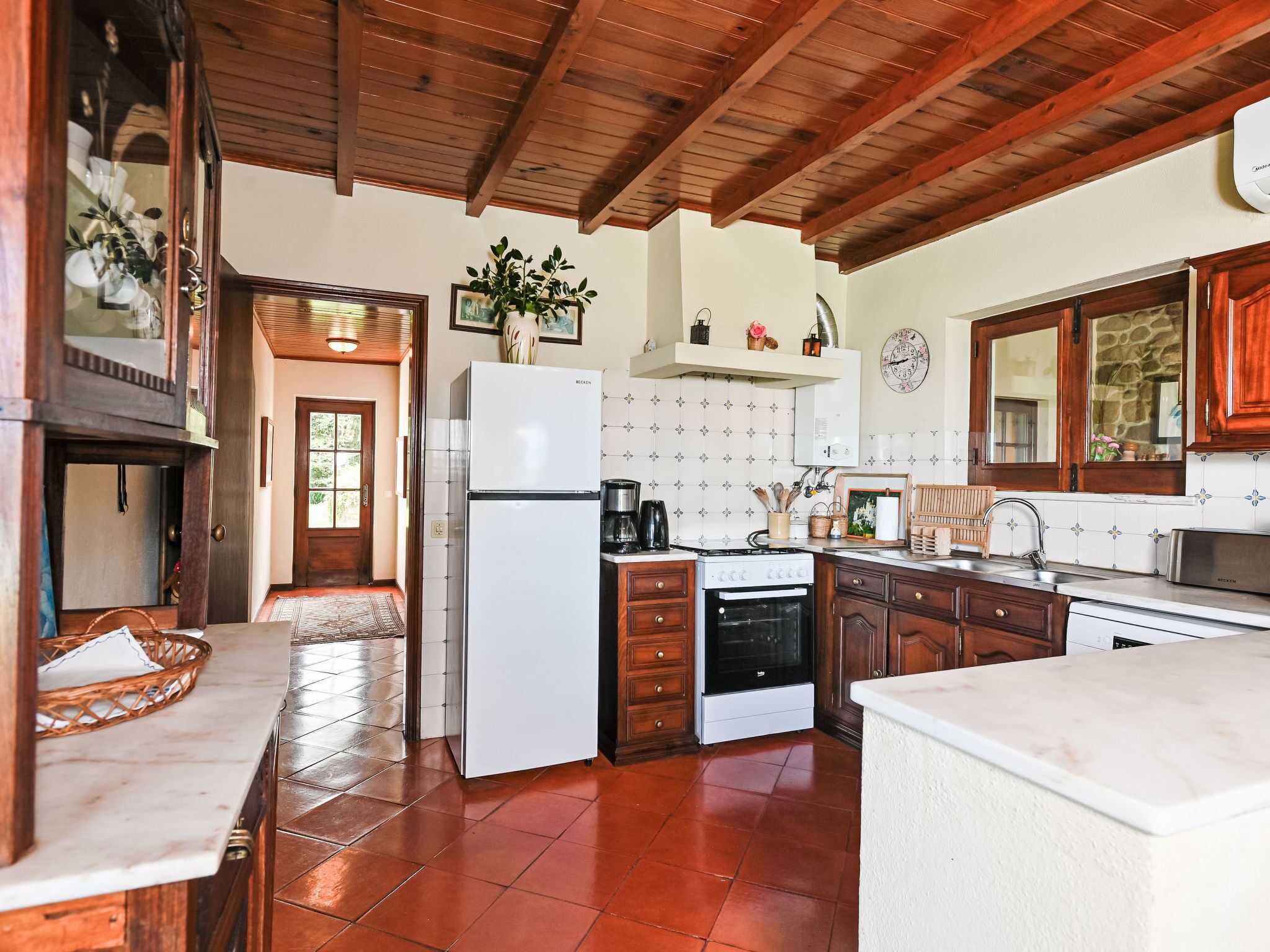 A kitchen with wooden cabinets, a refrigerator, stove, and a sink.