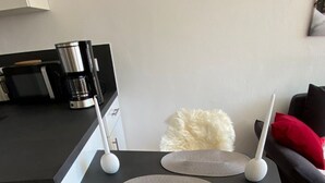 Moderni keittiö, jossa on musta työtaso, kahvinkeitin ja valkoinen tuoli, jossa on pehmeä istuin.