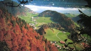Un paysage montagneux comprenant une vallée, un petit village et un lac.