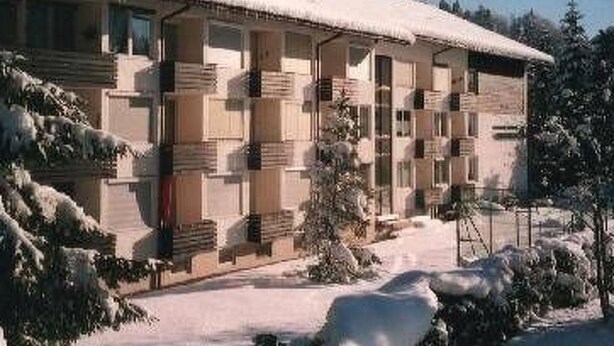 Un hôtel doté de nombreux balcons, d’un toit enneigé et surplombant un ciel dégagé.
