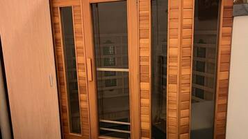 A room with a wooden wardrobe, a bed, and a small table.