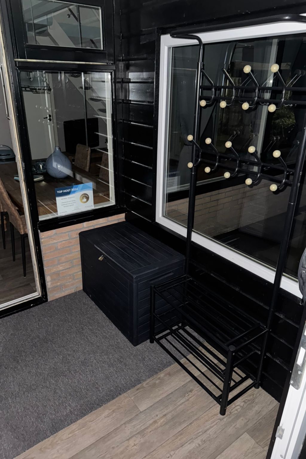 A room with a black metal bench, a white-framed window, and a mirror with a 'Top Host 2024' sign.