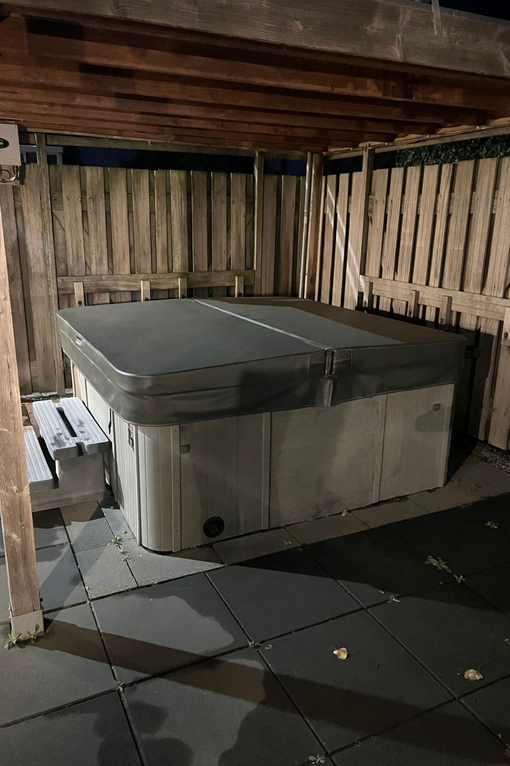A spa room with a large, rectangular hot tub, wooden panel walls, and a tiled floor.