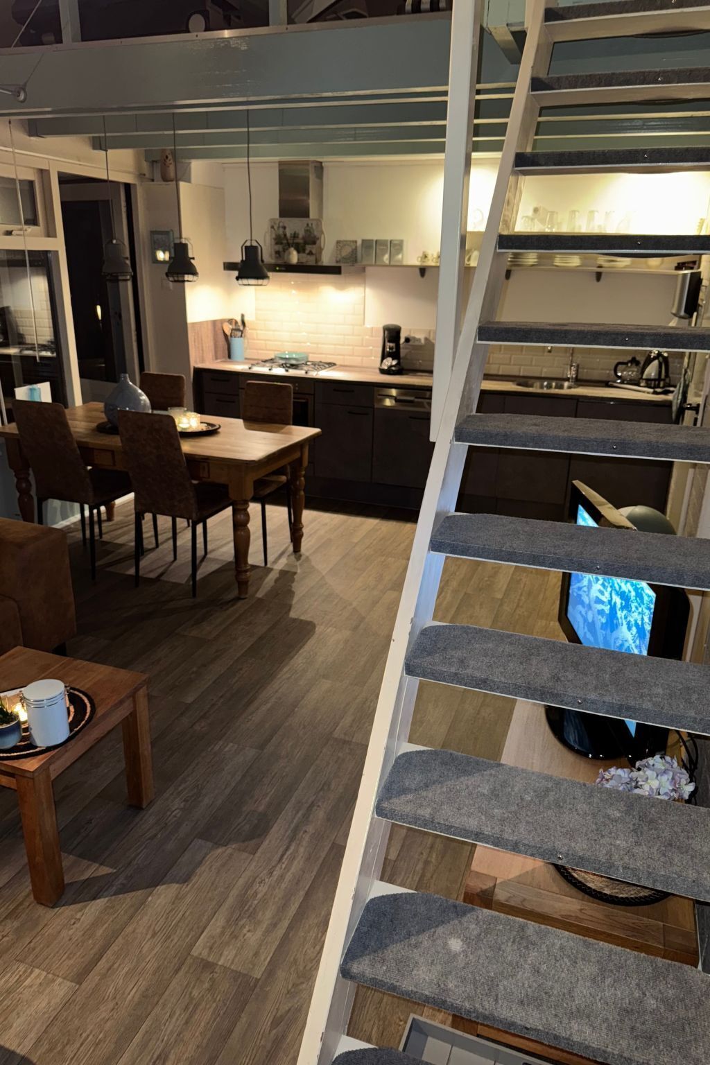 Een moderne keuken met een eethoek, een trap en een televisie.