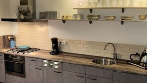 Une cuisine moderne avec des meubles gris, un évier en acier inoxydable et un four encastré.