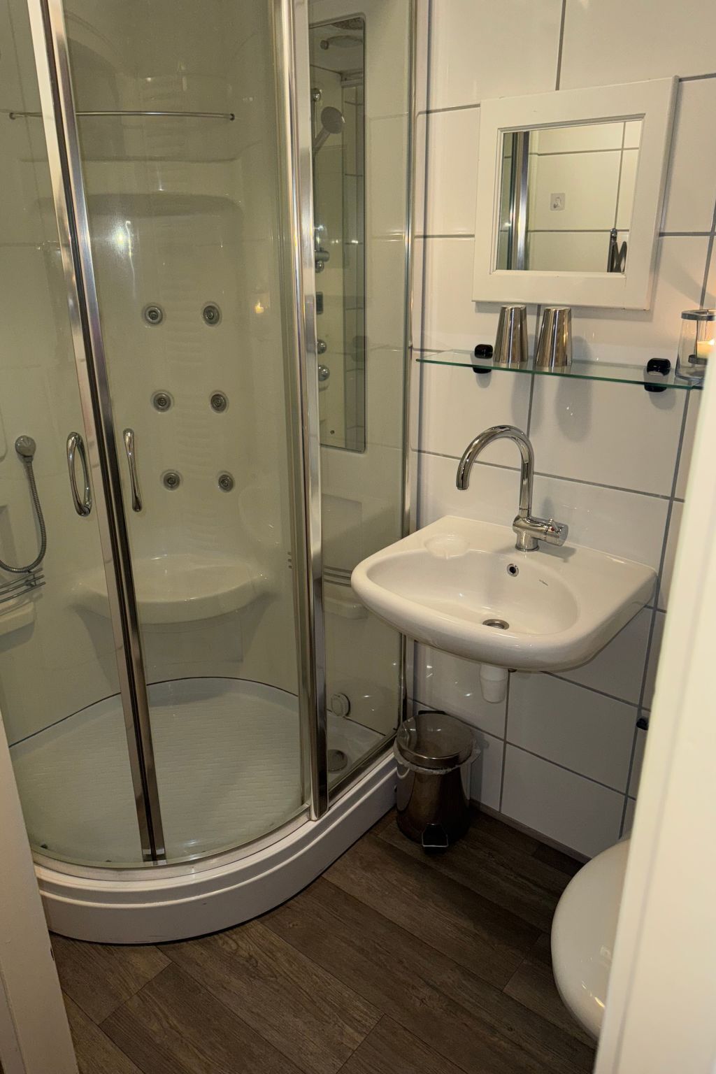 A bathroom with a glass-enclosed shower, a white sink, and a mirror above the sink.