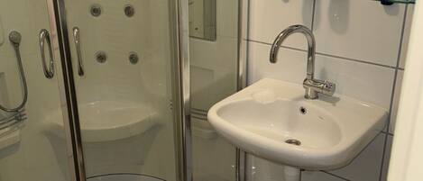 A bathroom with a glass-enclosed shower, a white sink, and a mirror above the sink.
