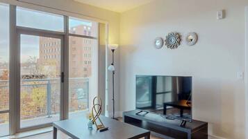 A modern living room with a large window, a flat-screen TV, and a minimalist decor.