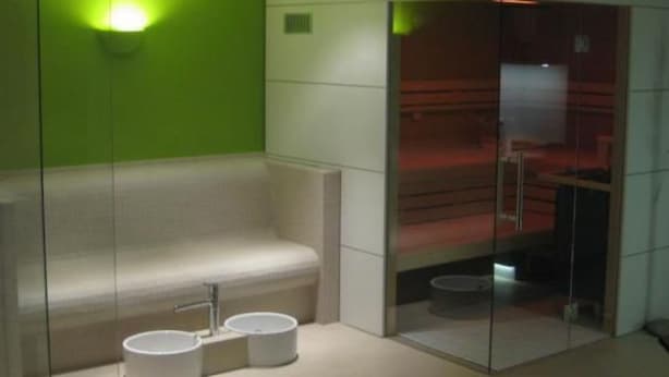 A modern bathroom with a glass enclosure, a bench, and two round sinks. - Apartment im Hotel Insel Pension in Niebüll by Interhome (Dagebüll)
