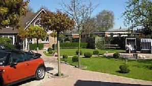 A residential driveway with a parked car, a lawn, and a house with a visible garage door. - Apartment im Hotel Insel Pension in Niebüll by Interhome (Dagebüll)