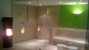 A modern bathroom with a glass-enclosed shower, a white bathtub, and a green accent wall. - Apartment im Hotel Insel Pension in Niebüll by Interhome (Dagebüll)