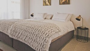 Un dormitorio con una cama grande, dos lámparas de noche y dos cuadros en la pared.