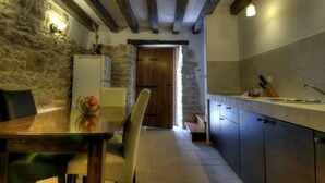 A rustic kitchen with exposed beams, a stone wall, and a wooden door leading to another room. - Istrien Traditionelles Steinhaus 7 by Interhome (Buzet)