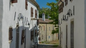 A narrow street with white buildings, wooden shutters, and outdoor lighting fixtures. - Istrien Traditionelles Steinhaus 6 by Interhome (Buzet)