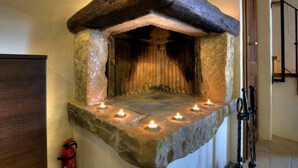 A stone-built fireplace with a wooden mantel and lit candles. - Istrien Traditionelles Steinhaus 6 by Interhome (Buzet)