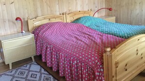 Una cama de madera con cabecera, dos mesitas de noche y una lámpara roja sobre una de ellas.