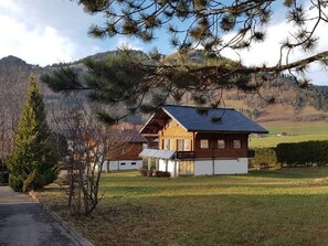 A wooden house with a sloped roof, surrounded by a grassy area and pine trees. - Chalet mit grossem Umschwung by Interhome (Charmey)