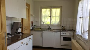 Una cocina con gabinetes blancos, una cafetera, un fregadero y una estufa.