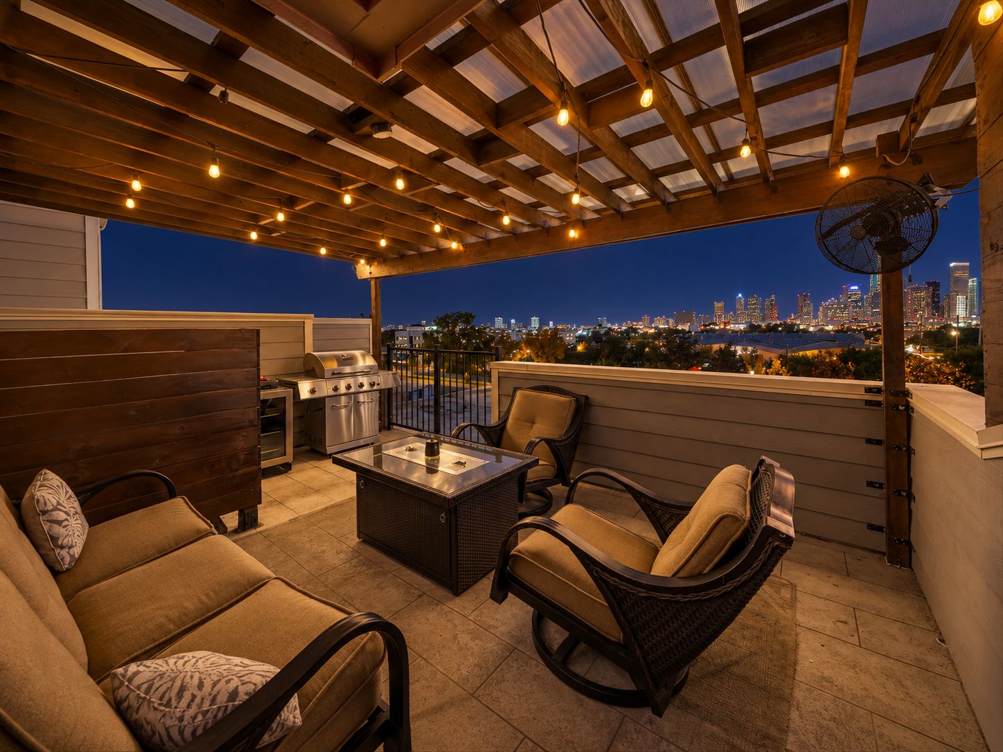 Eine Terrasse im Freien mit Grill, Sitzgelegenheit und Blick auf die Stadt im Abendlicht.