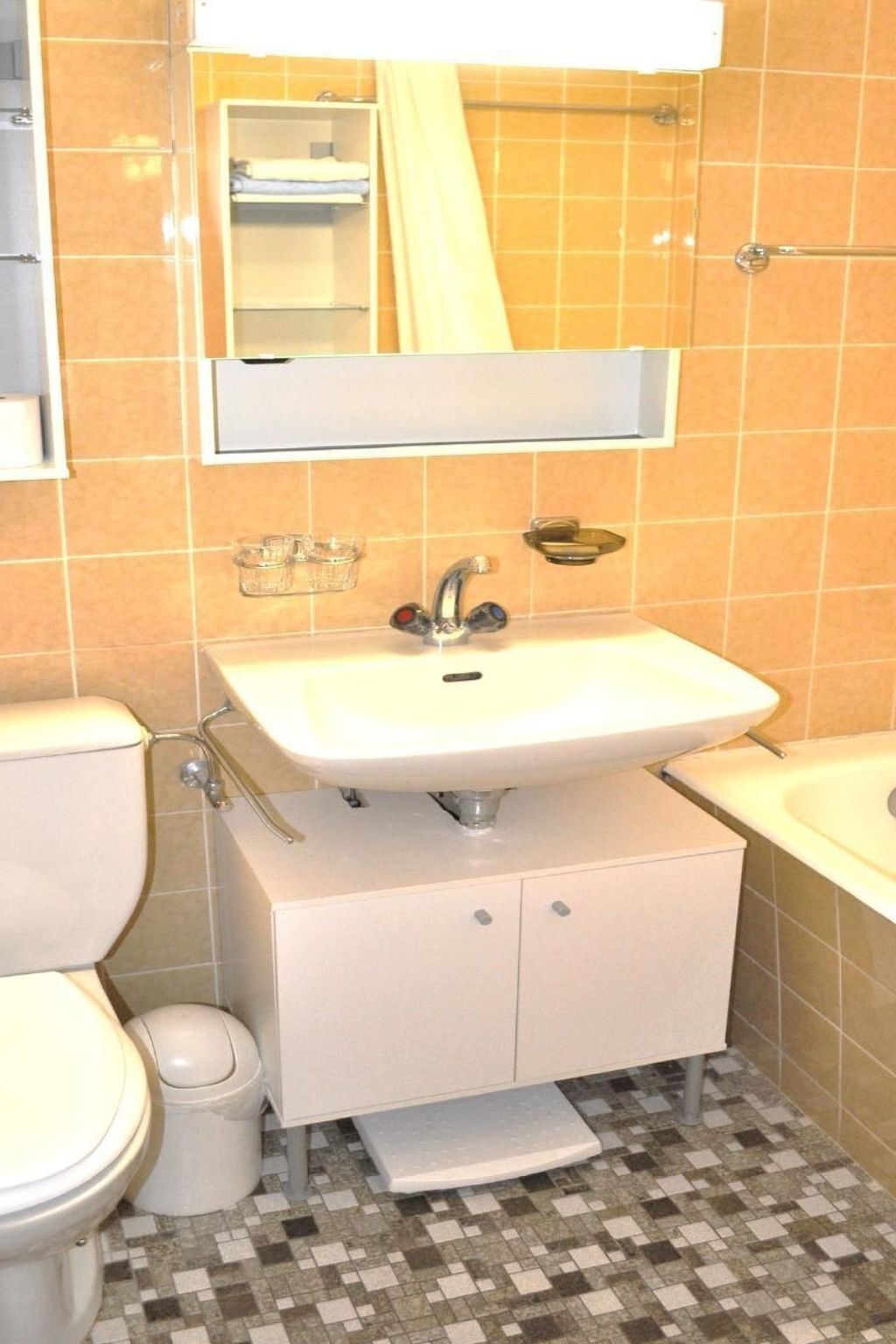 A bathroom with a white sink, a mirror above it, a toilet, and a shower area.