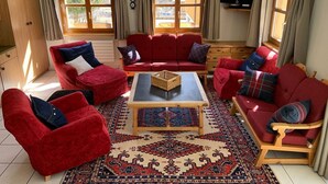 Ein geräumiges Wohnzimmer mit roten Sofas, einem Couchtisch und einem großen Teppich.