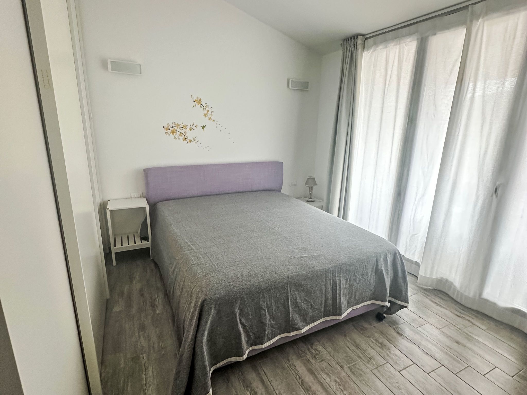 A bedroom with a bed, a nightstand, a lamp, and a window with curtains.