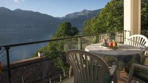 Un balcon avec une table et des chaises donnant sur un lac et des montagnes.