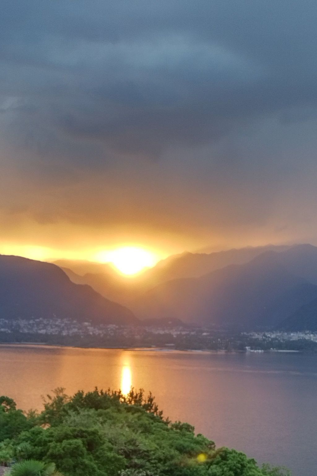 Ein Sonnenuntergang über einem stillen See vor einer Bergkulisse.