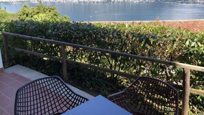 En balkon med udsigt over en sø og bjerge, med to stole og et bord.